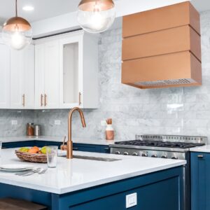 Copper - toned range hood in a vibrant kitchen with blue cabinetry