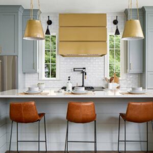 Golden - hued range hood in a contemporary kitchen with bar stools