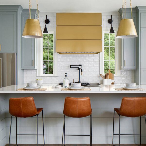 Golden - hued range hood in a contemporary kitchen with bar stools