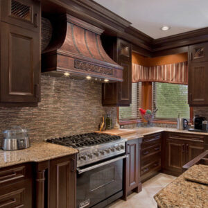 A grand, intricately - designed copper range hood taking center stage in a luxurious kitchen, above a high - end stove.